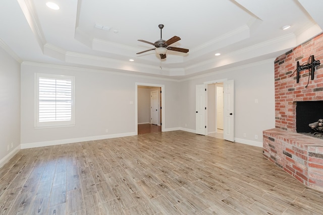 unfurnished living room featuring a raised ceiling, a fireplace, and light hardwood / wood-style flooring