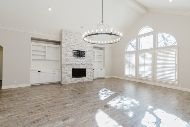 unfurnished living room with light hardwood / wood-style flooring, a notable chandelier, ornamental molding, a stone fireplace, and beamed ceiling