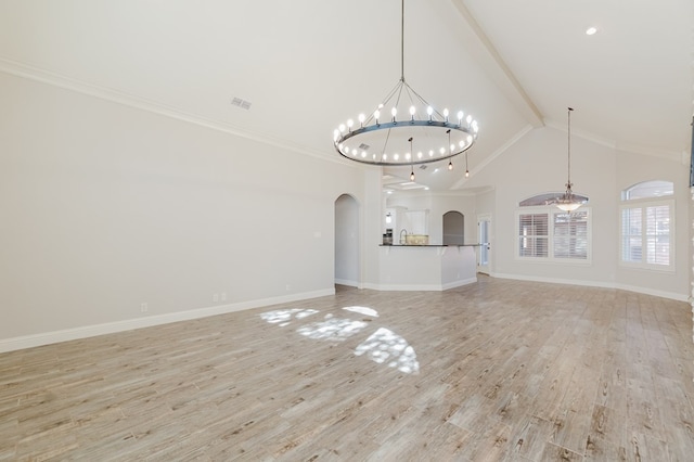 unfurnished living room with high vaulted ceiling, beamed ceiling, ornamental molding, an inviting chandelier, and light hardwood / wood-style flooring