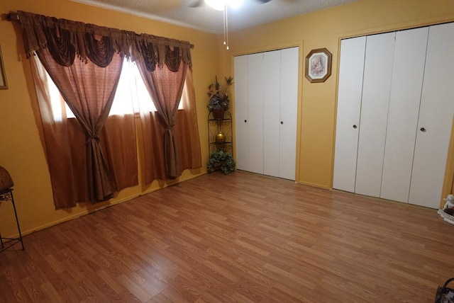 2511 Fontana St, Odessa, TX 79763 - unfurnished bedroom with two closets, wood finished floors, a textured ceiling, and ceiling fan