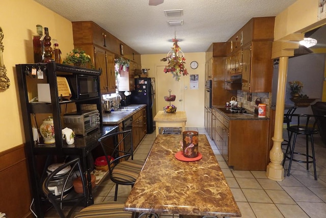 2511 Fontana St, Odessa, TX 79763 - kitchen featuring dark countertops, light tile patterned floors, black appliances, range hood, and a textured ceiling