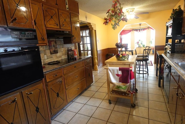 2511 Fontana St, Odessa, TX 79763 - kitchen with black appliances, under cabinet range hood, a wainscoted wall, plenty of natural light, and a ceiling fan