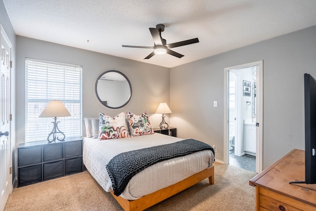 bedroom featuring connected bathroom, a ceiling fan, a textured ceiling, and light colored carpet