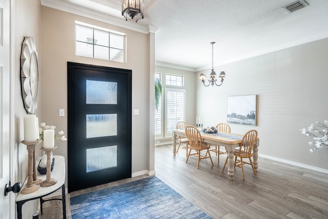 entryway with a notable chandelier, visible vents, ornamental molding, wood finished floors, and baseboards