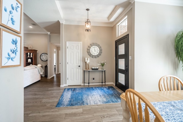 entryway with baseboards, a raised ceiling, wood finished floors, and crown molding