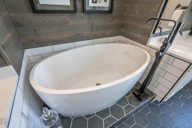 full bath featuring a freestanding bath, vanity, and tile patterned floors