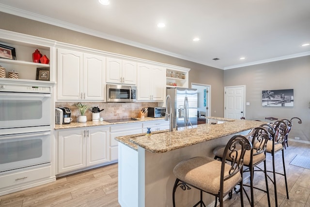 kitchen with light wood-style floors, stainless steel appliances, open shelves, and crown molding