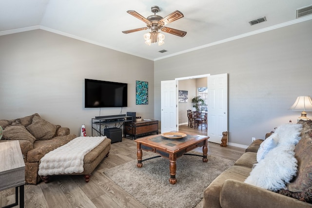 living room featuring visible vents, lofted ceiling, ceiling fan, wood finished floors, and crown molding