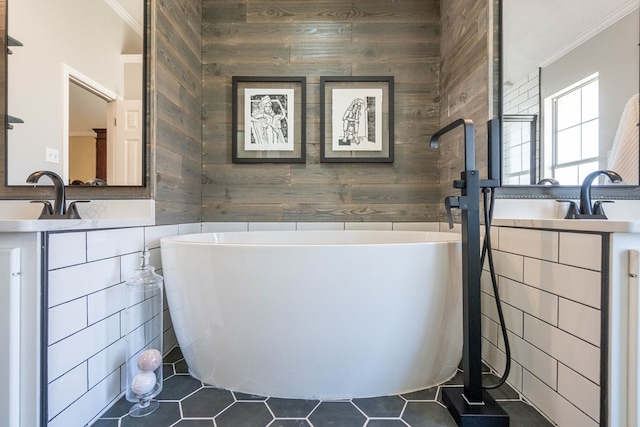 bathroom featuring ornamental molding, a sink, wooden walls, and a freestanding bath