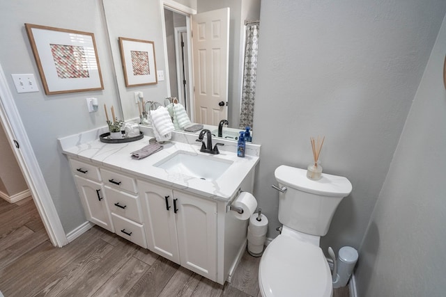 full bath featuring vanity, wood finished floors, toilet, and baseboards