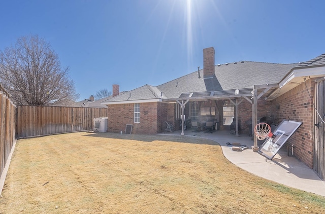 back of house with a fenced backyard, a yard, a patio area, a pergola, and brick siding