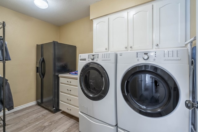 laundry area featuring washer and dryer, cabinet space, a textured ceiling, light wood-type flooring, and baseboards