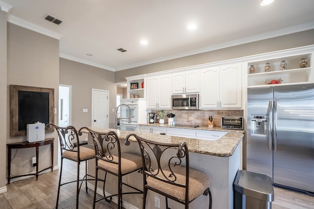 kitchen featuring open shelves, stainless steel appliances, visible vents, light wood-style floors, and a sink