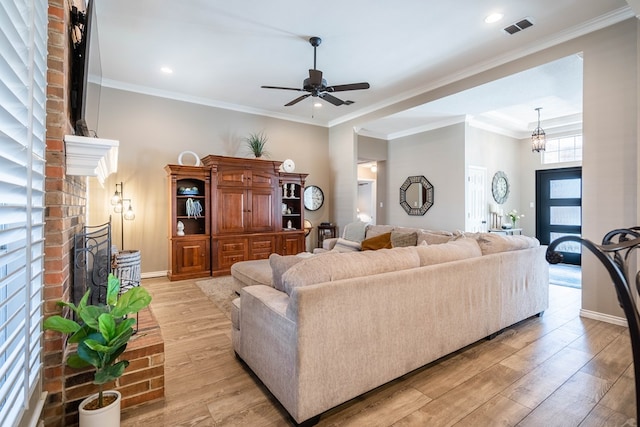 living room with ornamental molding, a fireplace, visible vents, and light wood-style floors