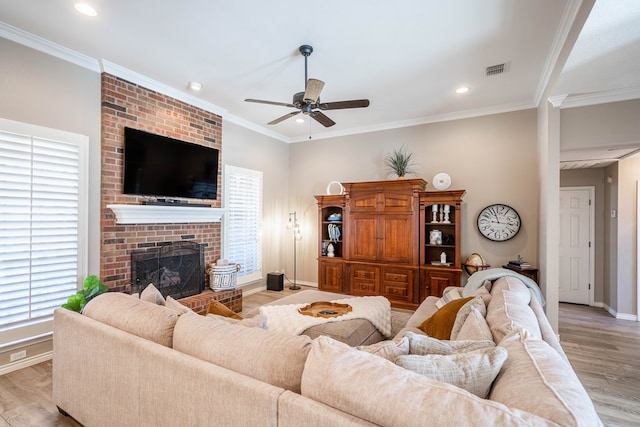 living room featuring visible vents, ornamental molding, a brick fireplace, and light wood-style flooring