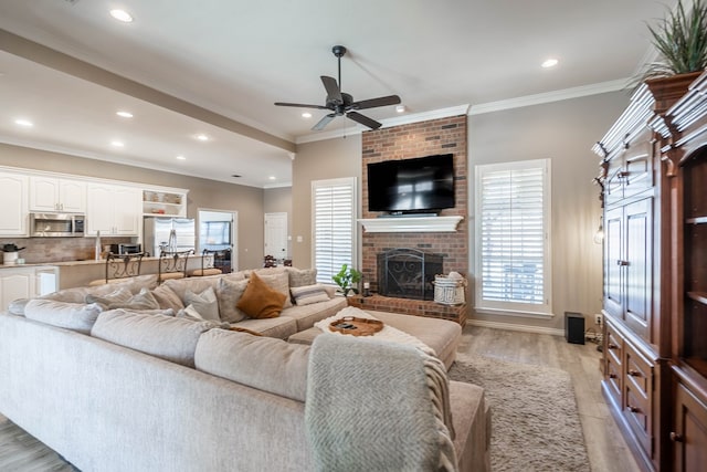 living area with light wood-style flooring, ceiling fan, ornamental molding, a fireplace, and recessed lighting