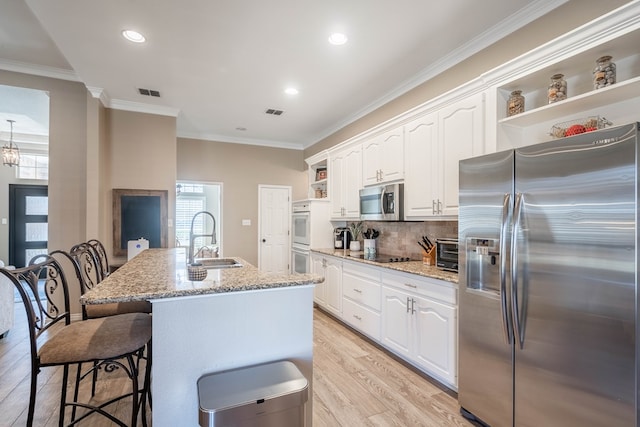 kitchen with plenty of natural light, appliances with stainless steel finishes, open shelves, and a sink