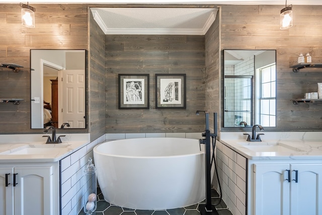 full bath featuring crown molding, two vanities, a sink, wood walls, and a freestanding tub