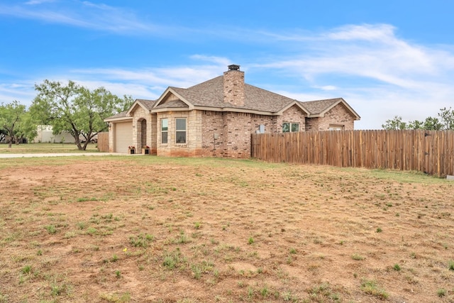 602 Frank Davis Ave, Coahoma, TX 79720 - view of property exterior with an attached garage, a chimney, and stone siding
