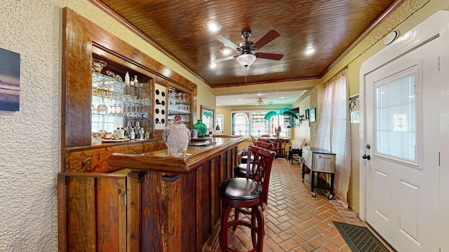 bar featuring wooden ceiling, ceiling fan, and ornamental molding