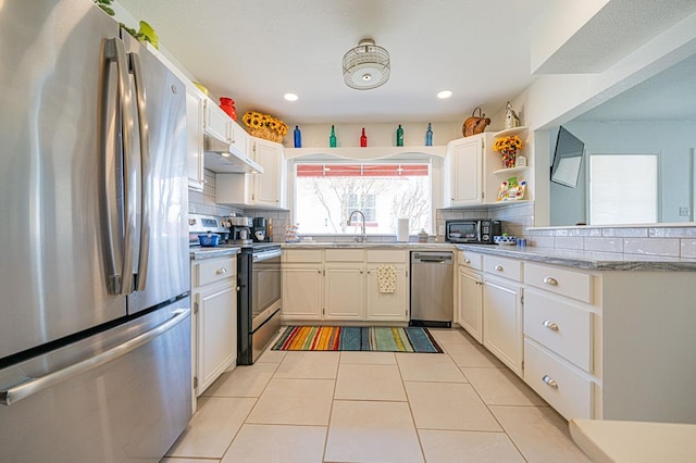 kitchen with backsplash, white cabinetry, light tile patterned floors, and stainless steel appliances