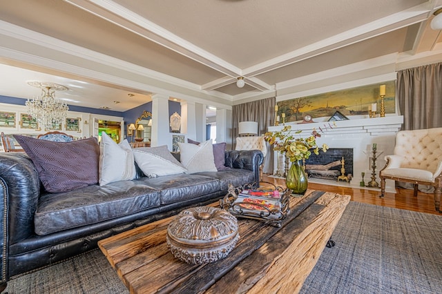 living room featuring coffered ceiling, a notable chandelier, decorative columns, hardwood / wood-style flooring, and ornamental molding