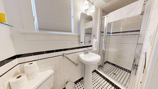 bathroom with an enclosed shower, toilet, and tile walls