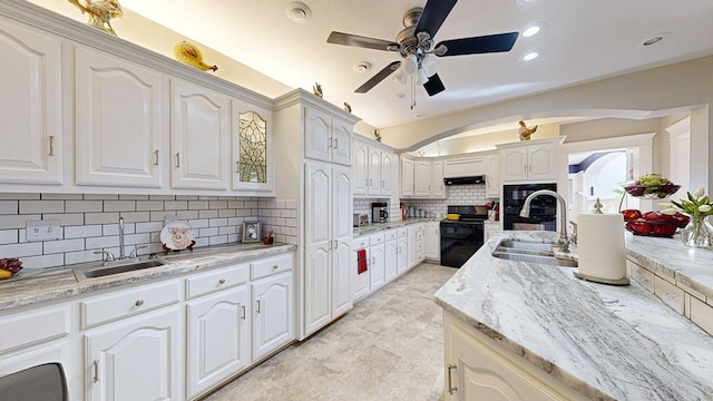 kitchen featuring white cabinets, tasteful backsplash, sink, and black / electric stove