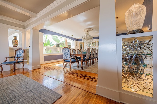 dining room featuring decorative columns, crown molding, hardwood / wood-style floors, and a notable chandelier