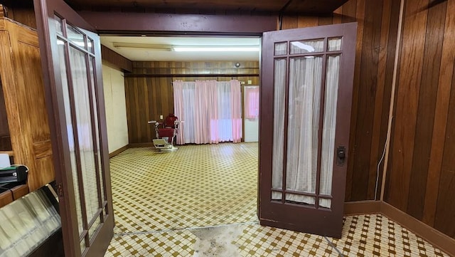 hall with wood walls, baseboards, light floors, and beam ceiling