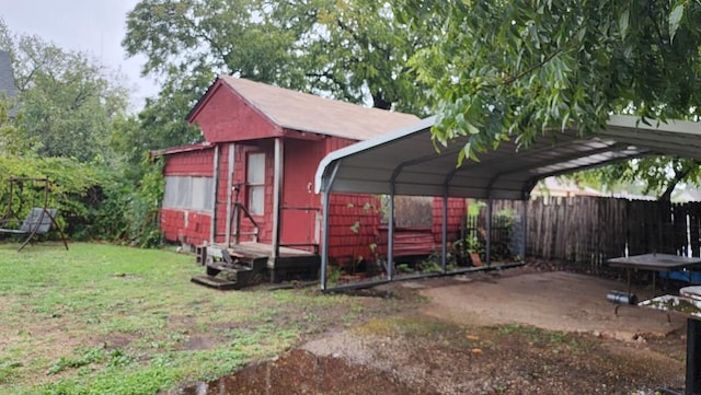 view of outbuilding with fence and a detached carport