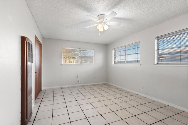 unfurnished room with ceiling fan, light tile patterned floors, and a textured ceiling