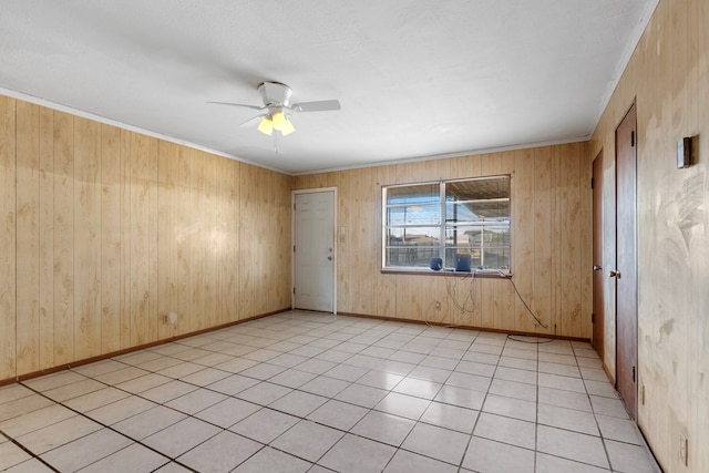 empty room featuring wooden walls, ceiling fan, and light tile patterned floors