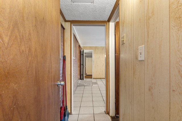 hallway featuring light tile patterned floors, crown molding, and wooden walls