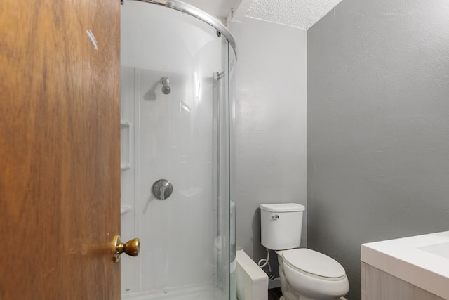 bathroom with an enclosed shower, vanity, toilet, and a textured ceiling