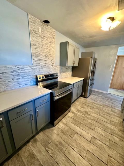 kitchen featuring appliances with stainless steel finishes, light hardwood / wood-style floors, and tasteful backsplash