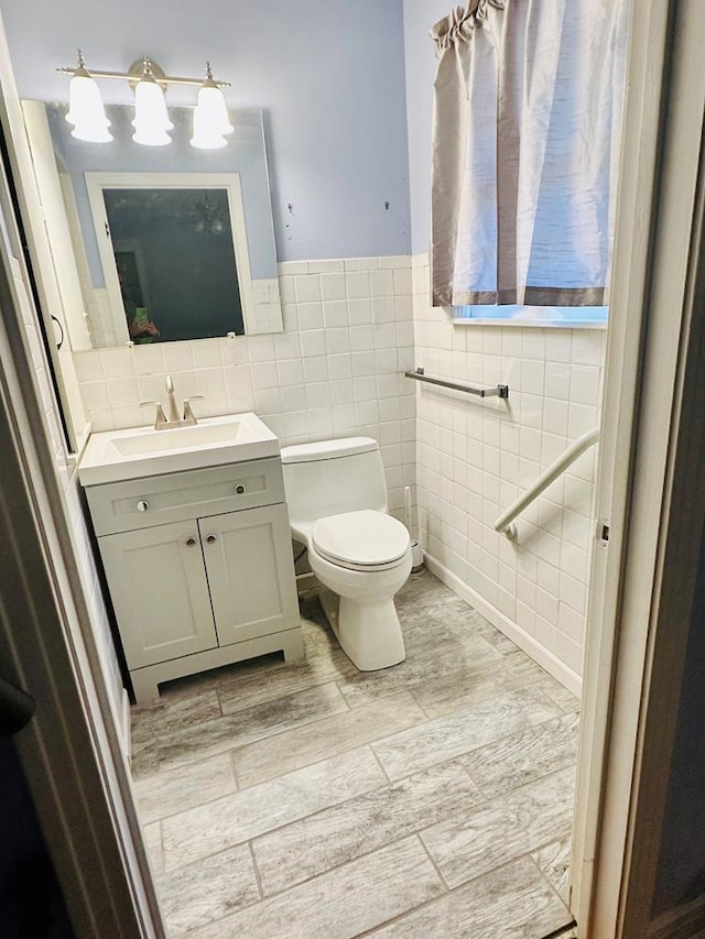 bathroom featuring vanity, toilet, and tile walls