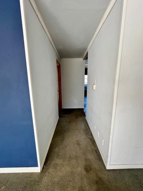 hallway featuring dark carpet and ornamental molding