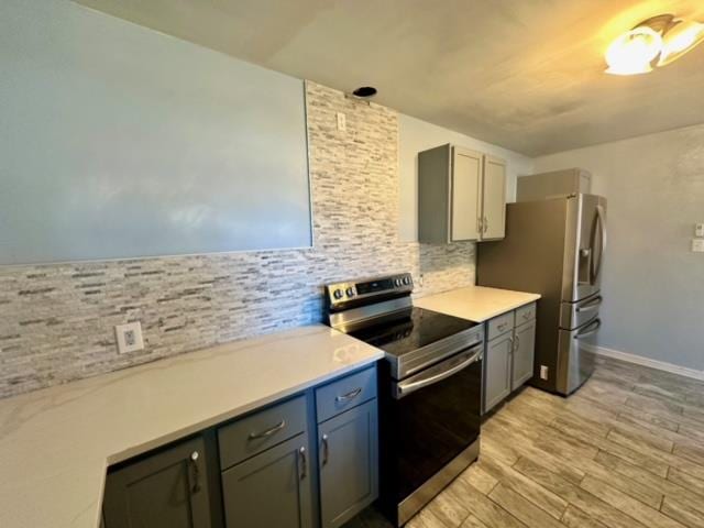 kitchen with decorative backsplash, gray cabinets, stainless steel appliances, and light hardwood / wood-style flooring