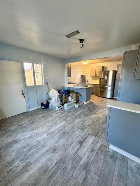 kitchen with a kitchen bar, stainless steel fridge, tasteful backsplash, dark hardwood / wood-style flooring, and kitchen peninsula