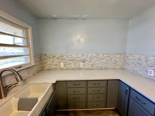 kitchen featuring gray cabinets, decorative backsplash, sink, and light stone counters