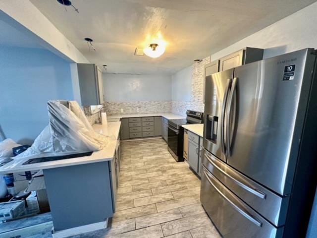 kitchen with black range with electric cooktop, stainless steel fridge, light hardwood / wood-style floors, decorative backsplash, and a breakfast bar