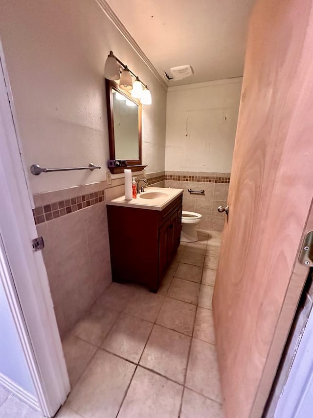 bathroom with vanity, tile patterned floors, toilet, ornamental molding, and tile walls