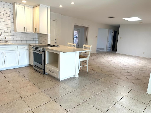 kitchen featuring light tile patterned floors, a peninsula, open floor plan, decorative backsplash, and stainless steel electric range oven