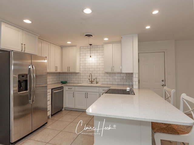 kitchen featuring a peninsula, a sink, visible vents, appliances with stainless steel finishes, and decorative backsplash