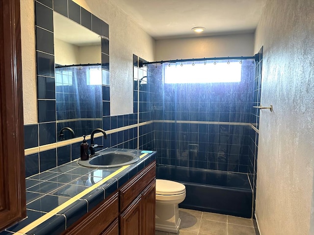 bathroom with a textured wall, tile patterned flooring, toilet, vanity, and bathing tub / shower combination