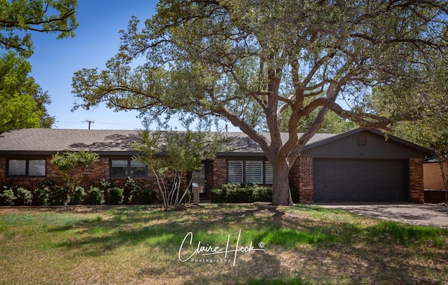 single story home with a garage, driveway, a front lawn, and brick siding