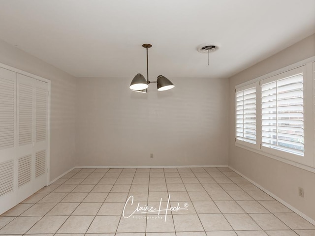 unfurnished dining area featuring visible vents, a notable chandelier, baseboards, and light tile patterned flooring