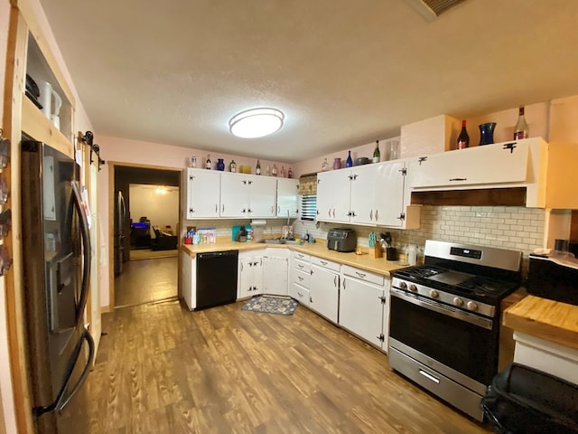 kitchen featuring white cabinetry, light hardwood / wood-style flooring, a textured ceiling, decorative backsplash, and black appliances