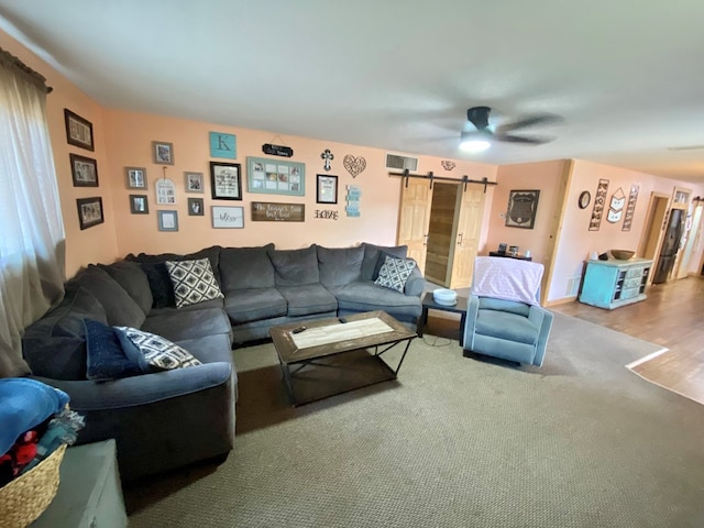 living room with a barn door, ceiling fan, and hardwood / wood-style flooring